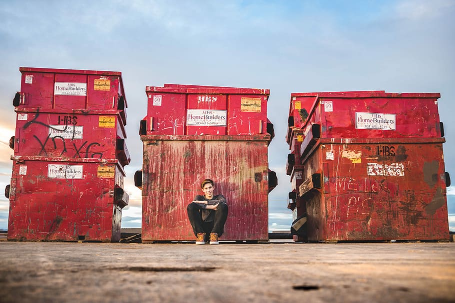 boy leaning while sitting at box, man sitting in front of red containers, HD wallpaper