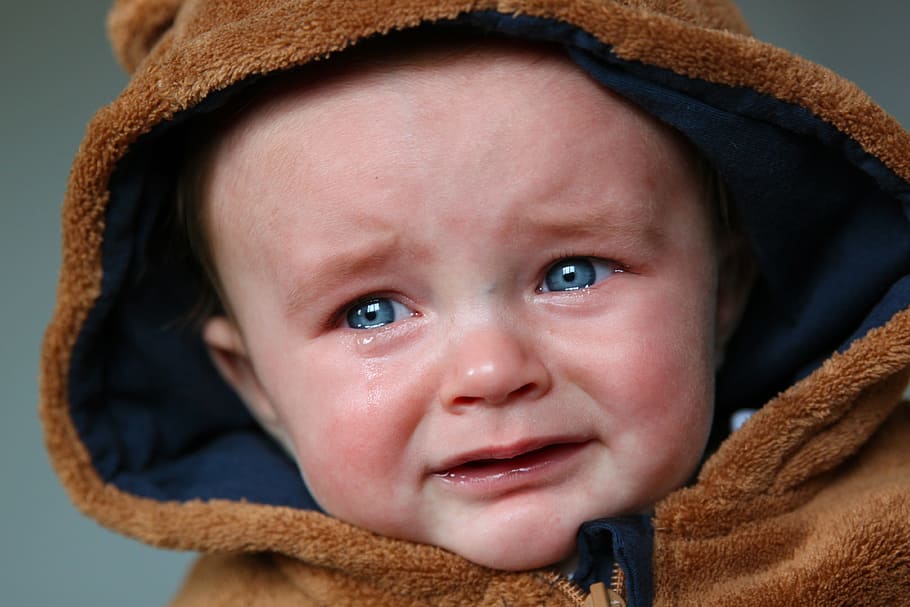 baby wearing brown suede zip-up hoodie, tears, small child, sad
