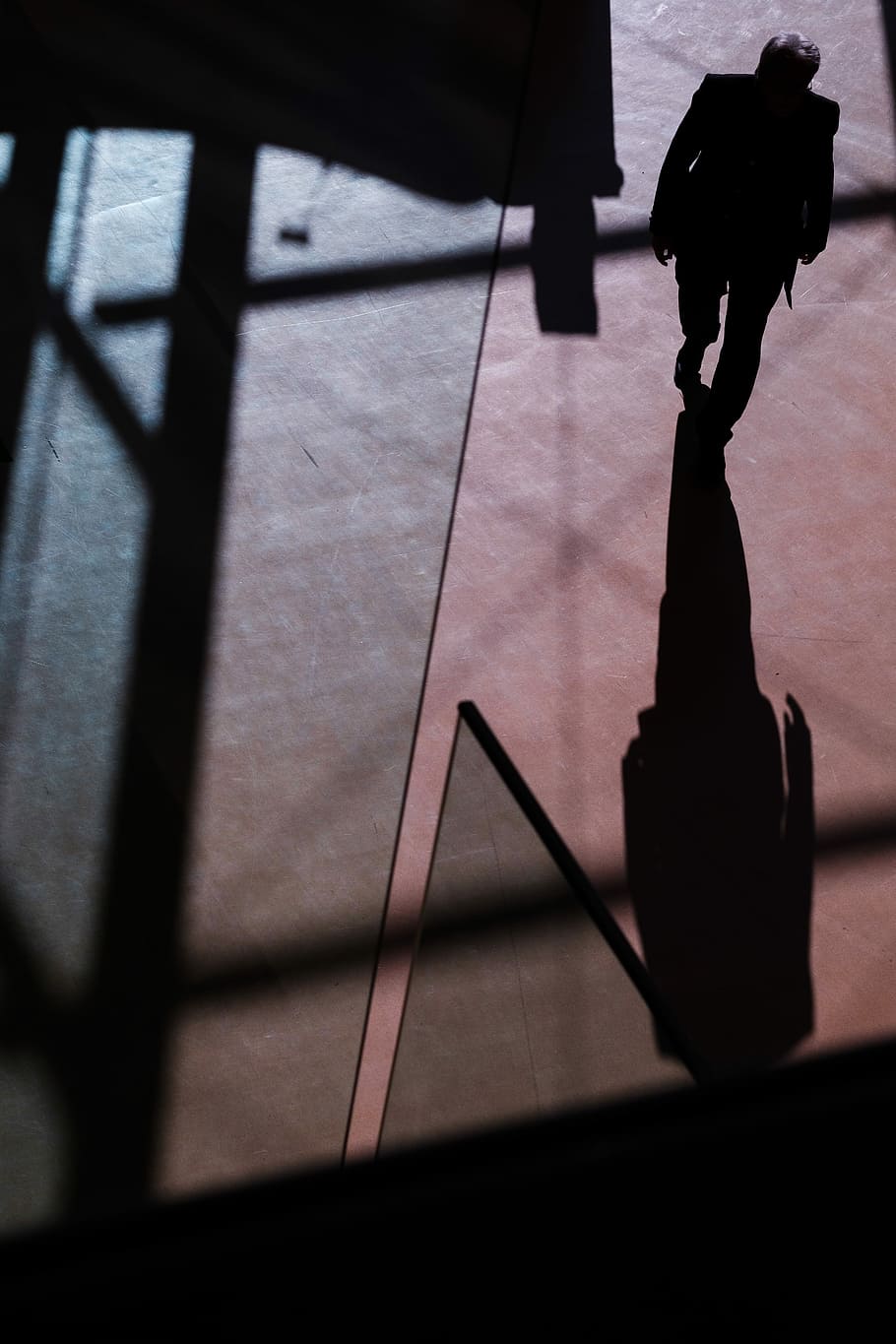 silhouette of person walking inside building, silhouette of man walking towards his shadow on orange concrete floor HD wallpaper