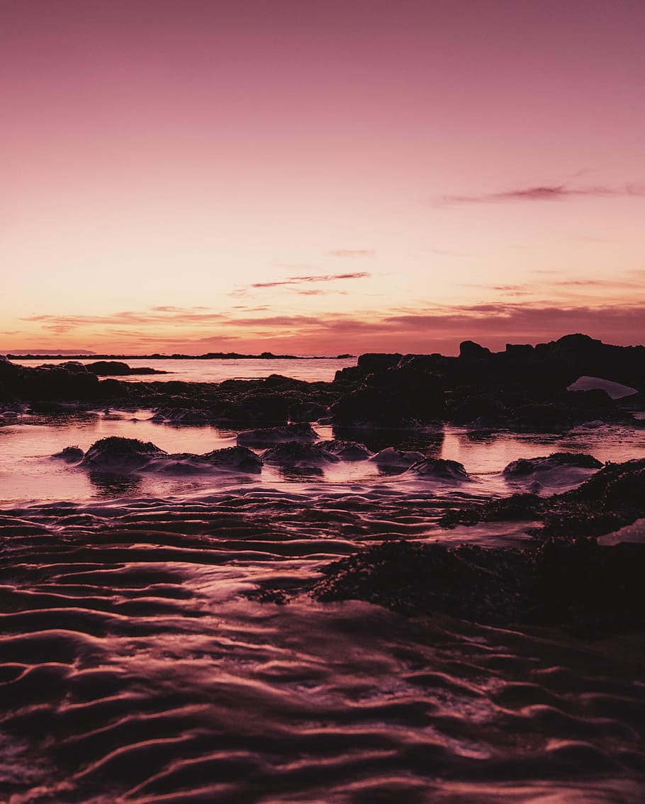 sea under gray clouds at golden hour, brown rock formation near body of water HD wallpaper