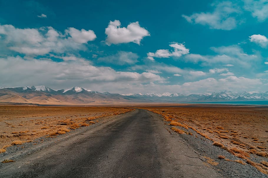 landscape photography of black road near brown grass field under cloudy blue sky HD wallpaper