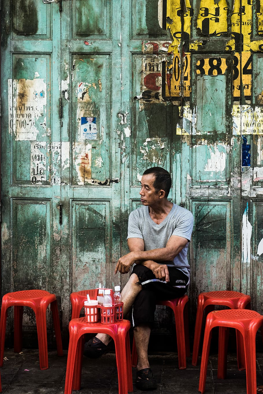 man sitting on red stool, man sitting on red plastic stool outdoor at daytime HD wallpaper