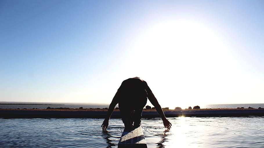 person kneeling on wood surface surrounded by body of water, silhouette photography of person about to dive HD wallpaper