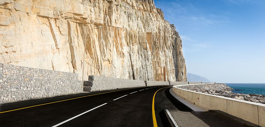 architectural photography of gray road, photo of black asphalt road beside ocean shore HD wallpaper