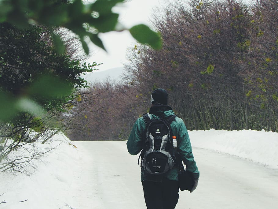 shallow focus photography of person in green winter jacket walking on snow covered field during nighttime HD wallpaper