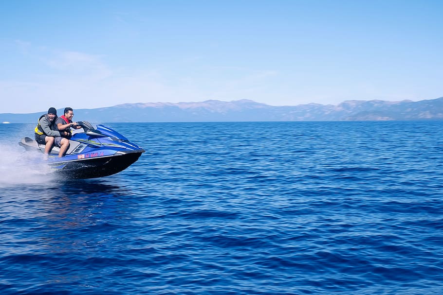 two men riding personal watercraft on blue calm sea at daytime