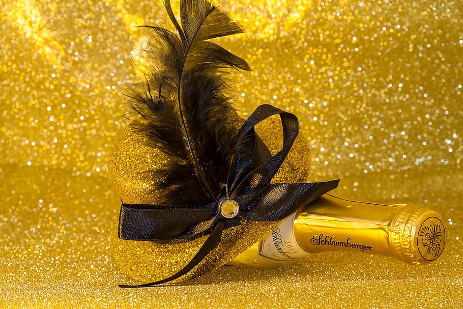 closeup photo of liquor bottle with feather decor, new year's eve