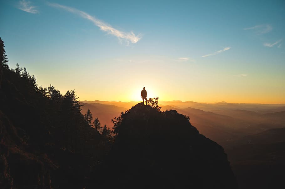 silhouette of man standing on mountain peak, silhouette of man standing on hill facing sunset