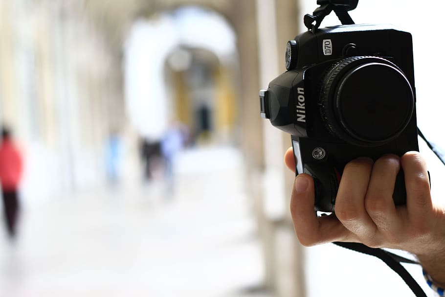 person holding black Nikon D70 in tilt shift lens photography HD wallpaper