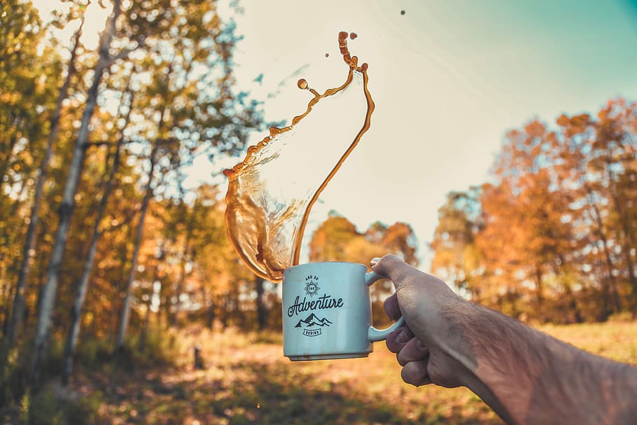 shallow focus photography of person spilling coffee from mug, person's hand holding mug HD wallpaper