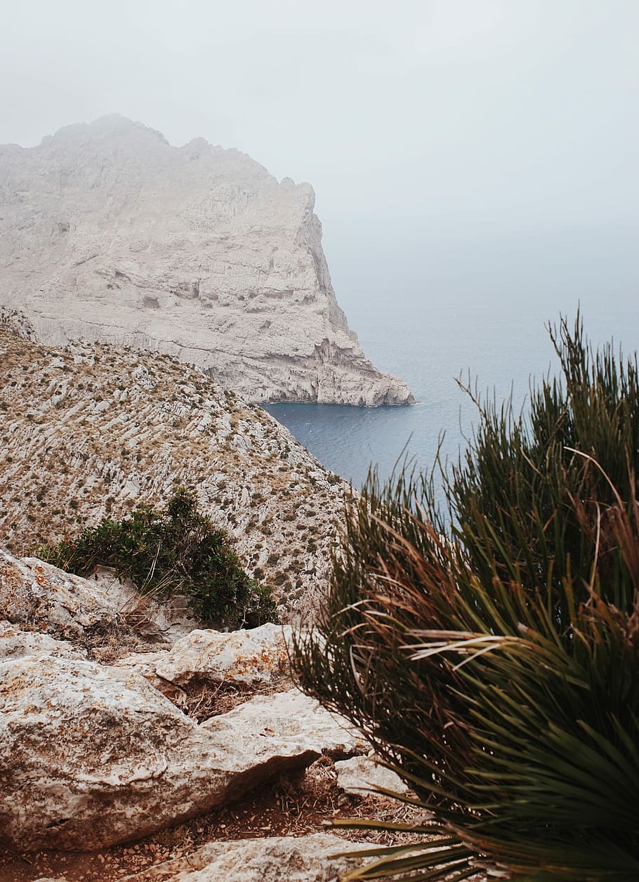 high angle photography of cliff near beach, mountains and body of water during daytime HD wallpaper