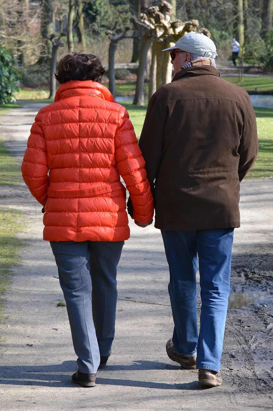 man and woman wearing jacket walking on pathway during daytime HD wallpaper