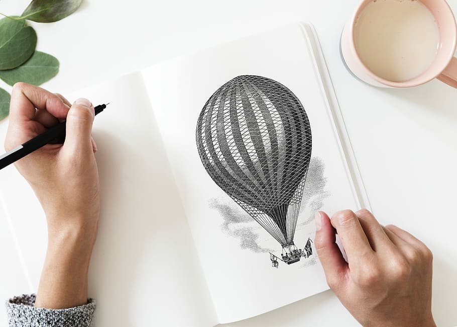 person drawing a hot air balloon on a illustration pad, woman