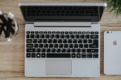 Silver Acer laptop on a wooden desk with a green plant, pencils and an Apple iPhone HD wallpaper
