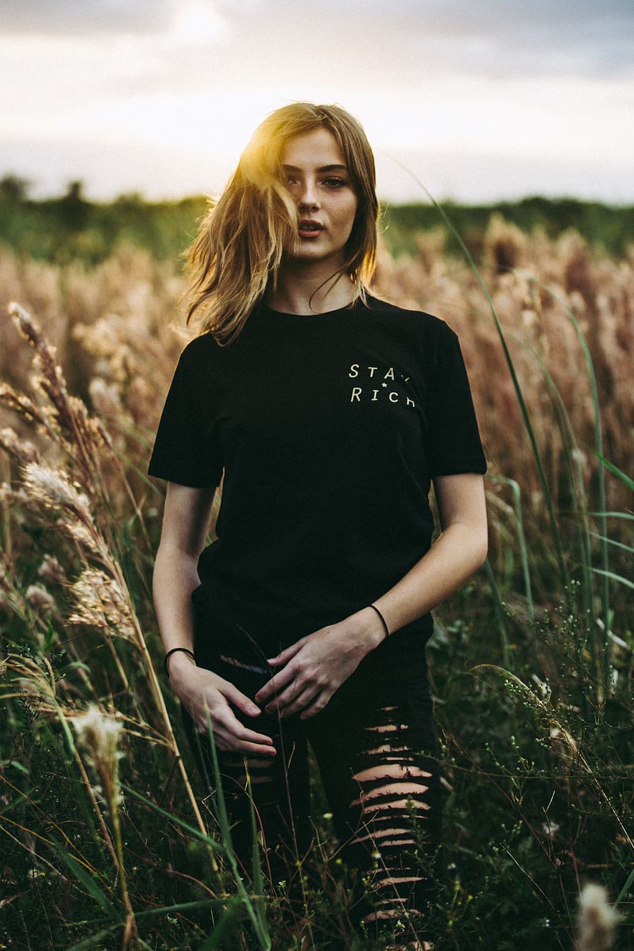 selective focus photography of black crew-neck t-shirt and distressed black bottom standing on brown wheat field during daytime, woman in black crew-neck t-shirt standing on wheat field, HD wallpaper