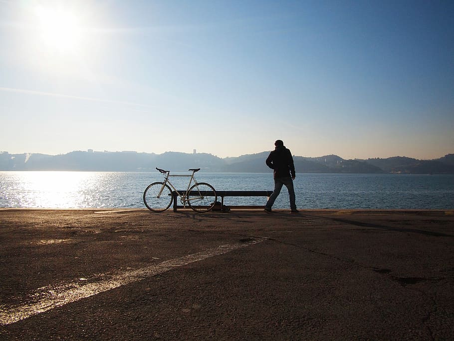 silhouette of man beside white fixie bike watching ocean water view during daytime HD wallpaper