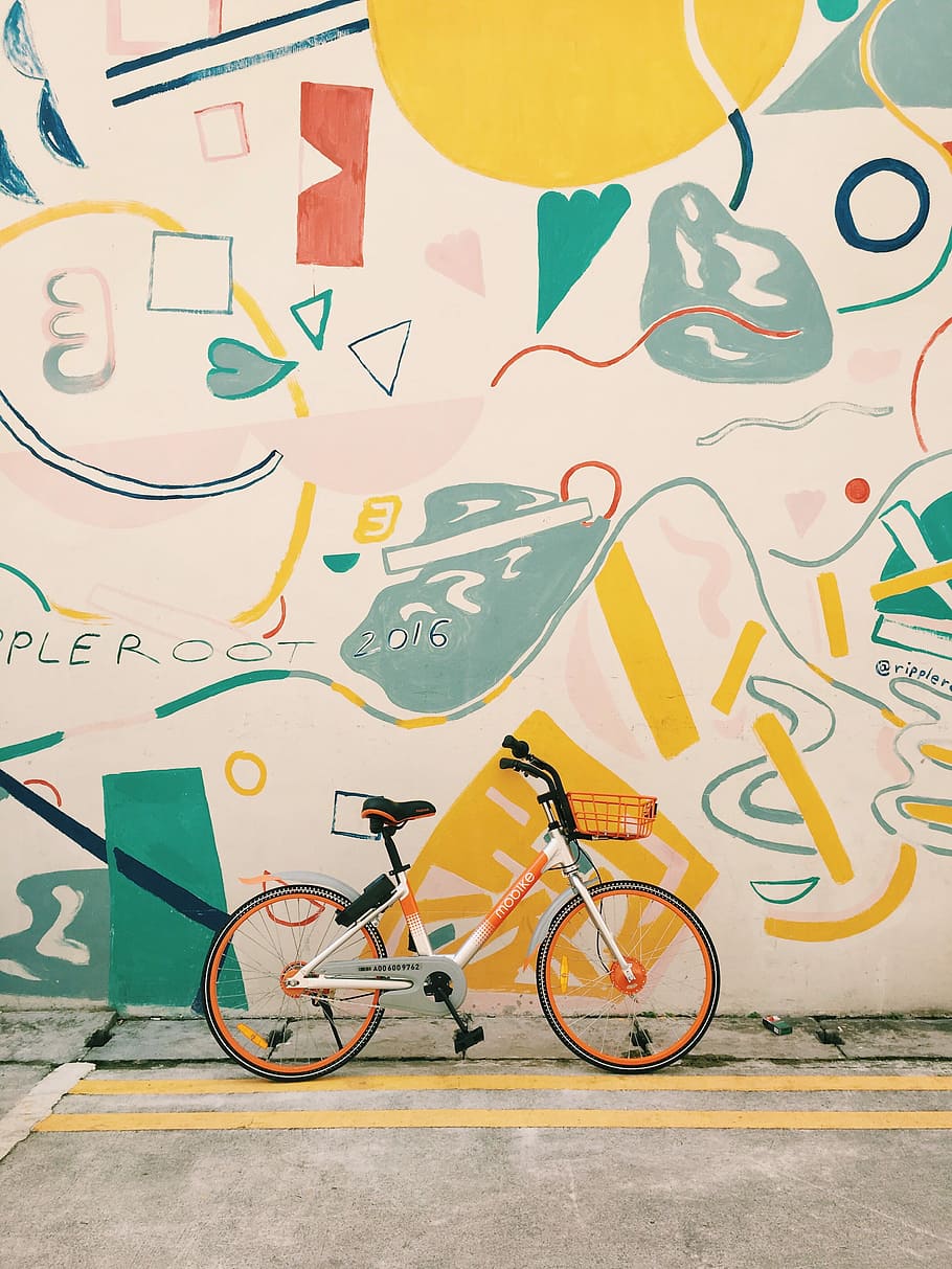 photography of orange and white bicycle, bicycle standing near painted wall