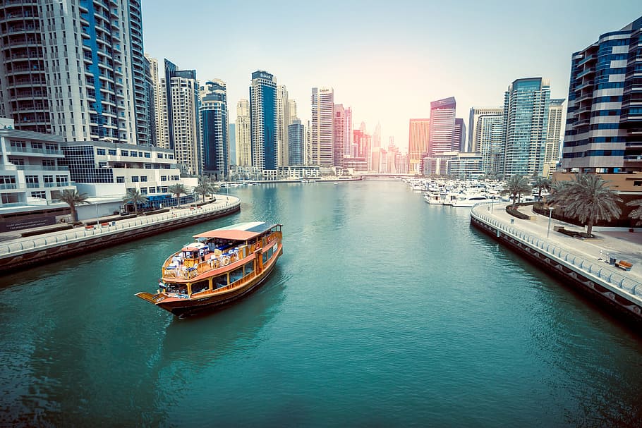 brown boat on body of water, brown passenger boat sailing on river between city buildings during daytime HD wallpaper
