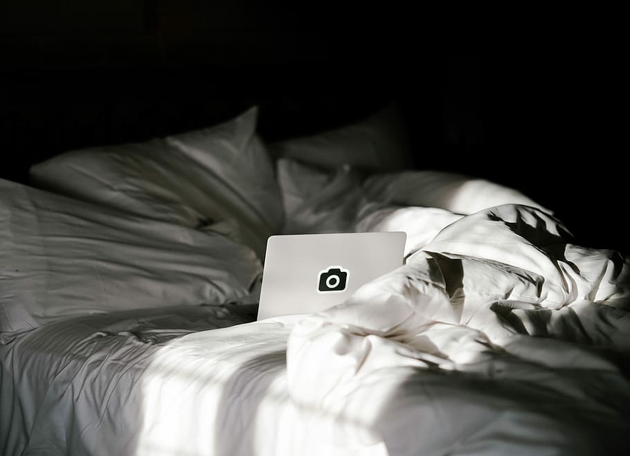 photography of gray laptop computer on the mattress, white laptop computer on white bedspread HD wallpaper