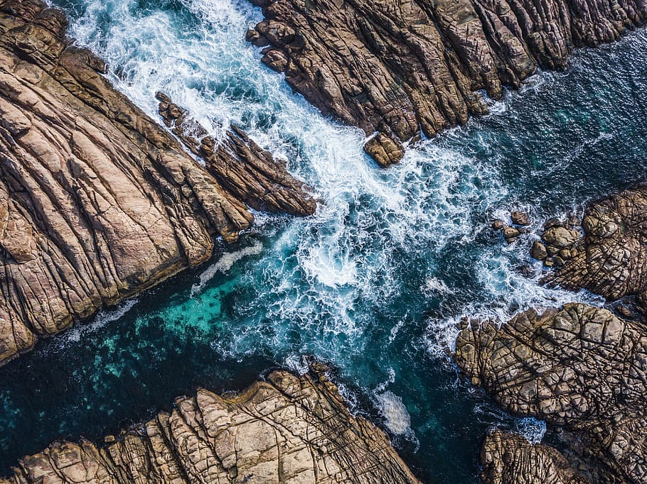 aerial view of ocean, bird's eye view photography of photo of body of water rushing through rocks