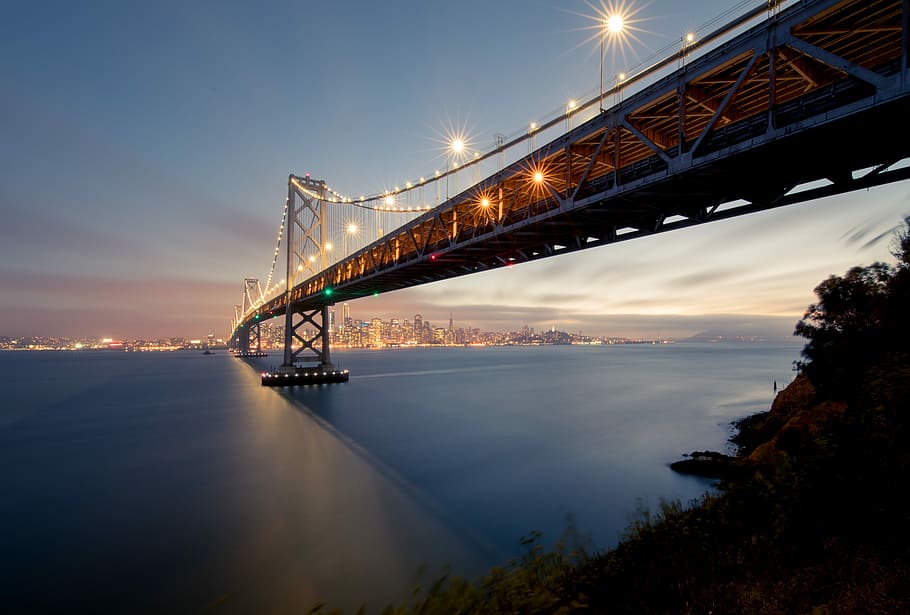 low angle photography of concrete bridge, black steel bridge over body of water during sunset HD wallpaper