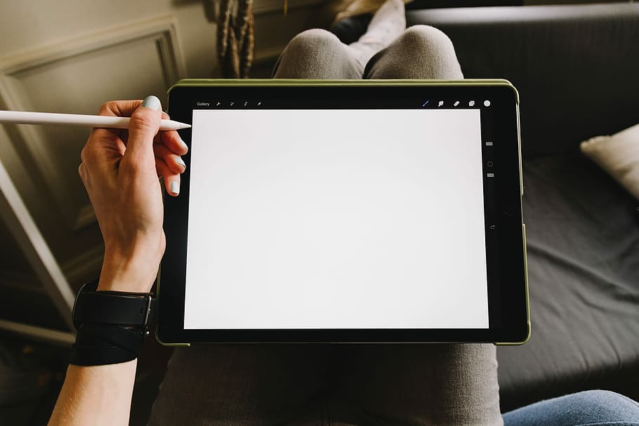 man holding iPad wand Apple Pencil, person holding a stylus pen beside black tablet computer