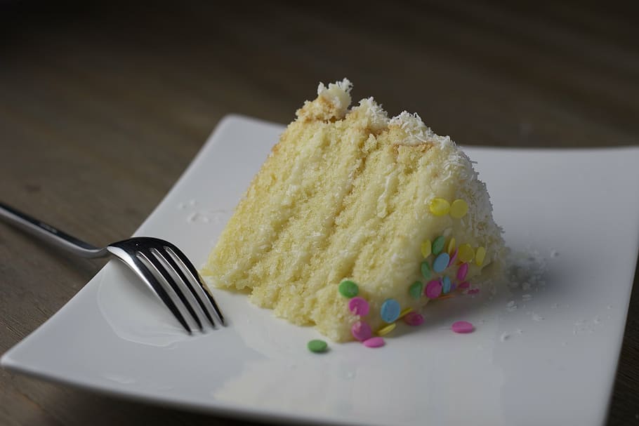 triangular sliced 4-layered cake beside gray stainless steel fork on square white ceramic plate HD wallpaper