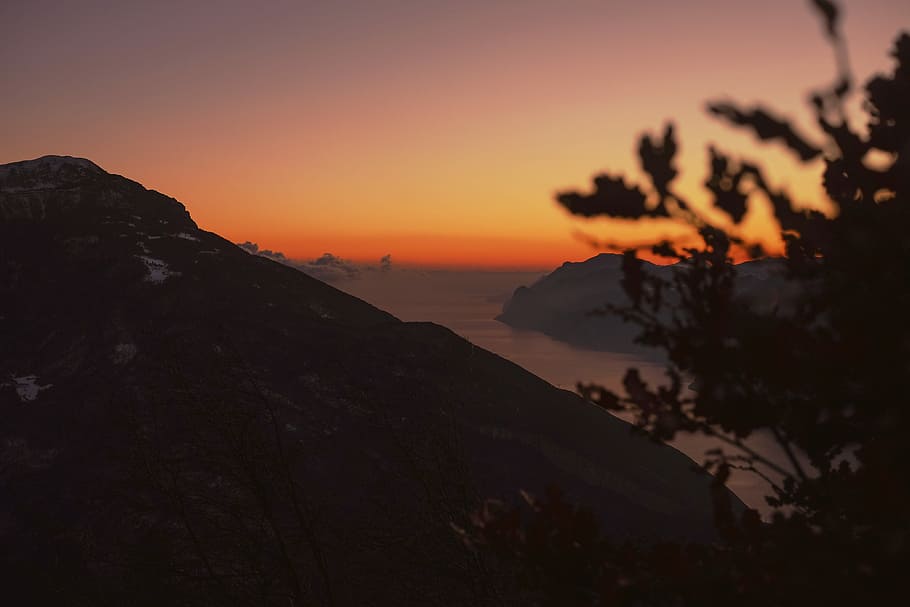 high-angle silhouette photography of mountain ranges with body of water in between during golden hour, silhouette photo of mountain near body of water HD wallpaper