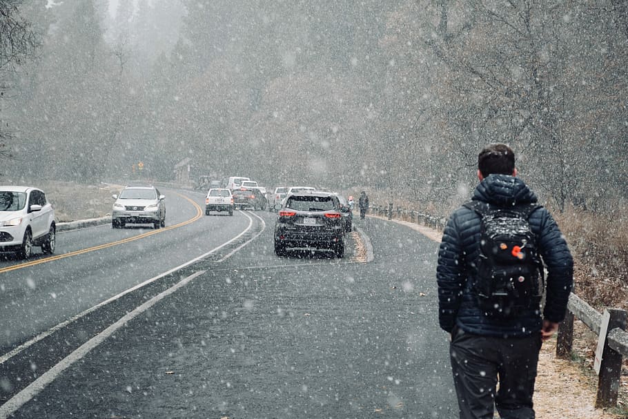 Walking in the snow, person walking on road beside moving vehicles during winter