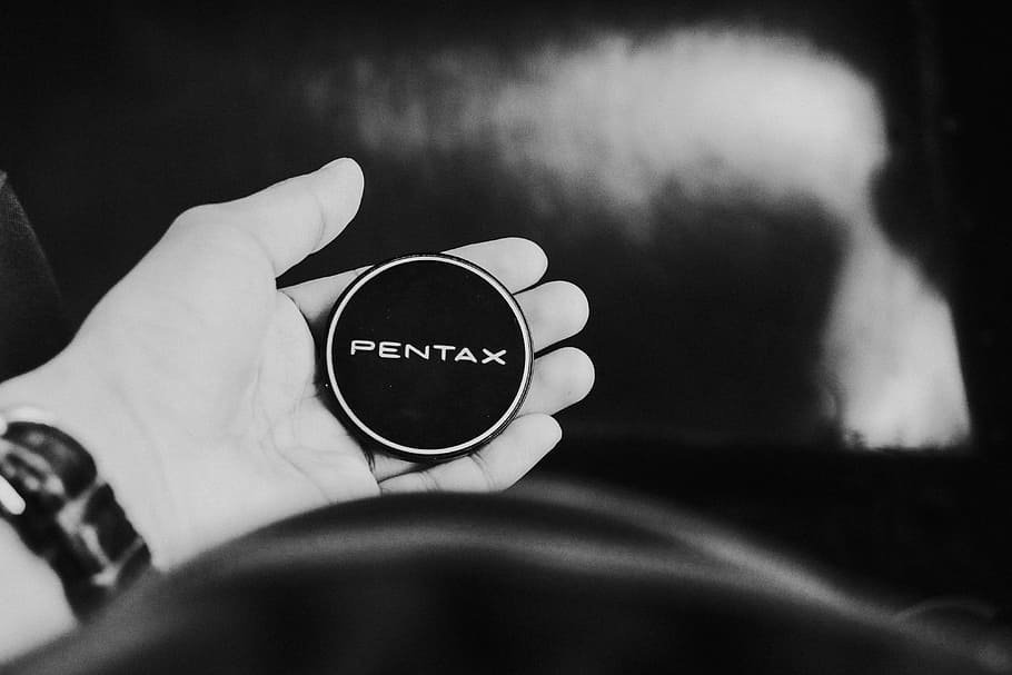 grayscaled photo of person's leeft hand, grayscale photo of person holding round Pentax cordless device HD wallpaper