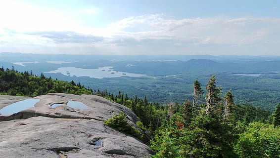 gray rock mountain during day time, brown cliff in front of forest HD wallpaper