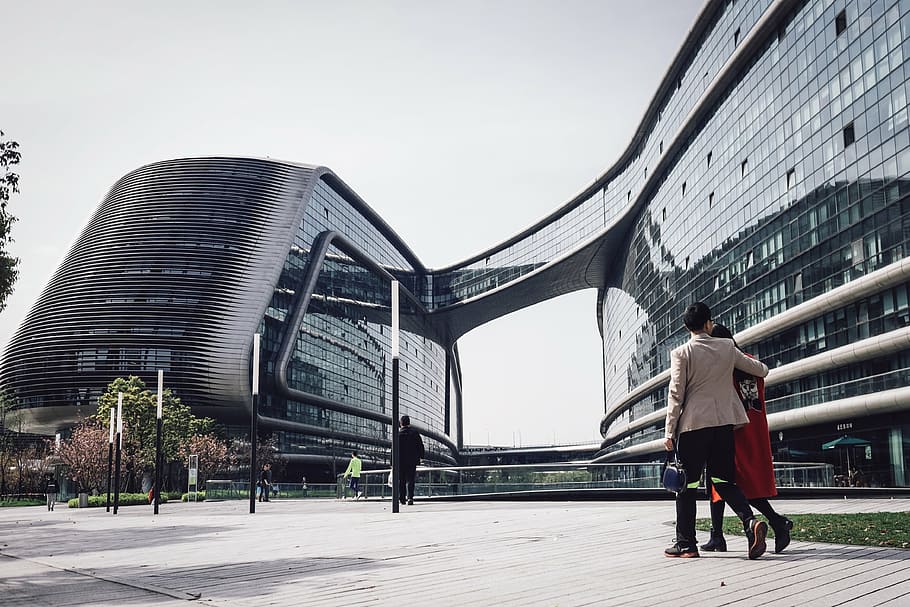 two person walking beside the glass building during daytime HD wallpaper