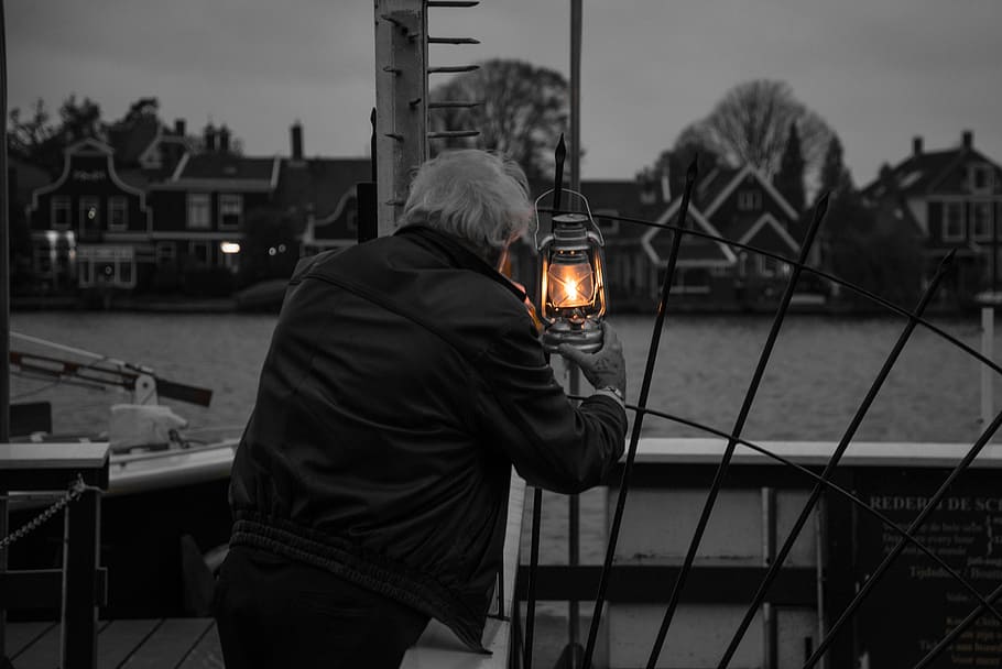 man holding lighted lantern watching over body of water, lights HD wallpaper