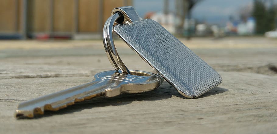 silver key on cement floor, keychain, metal, grey, shiny, color