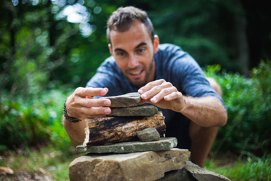 selective focus photography of man piling stones at daytime HD wallpaper