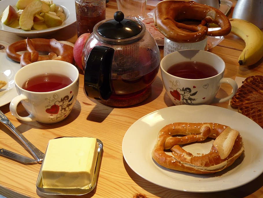 baked bread on white ceramic plate beside butter and cup of tea HD wallpaper