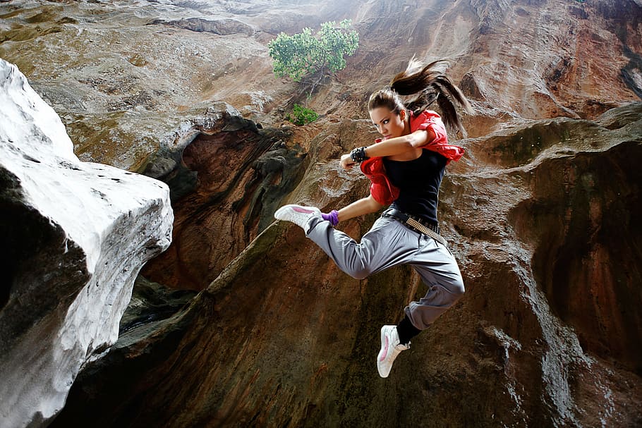 woman in black shirt jumping at the mountain, abyss, fighting stance