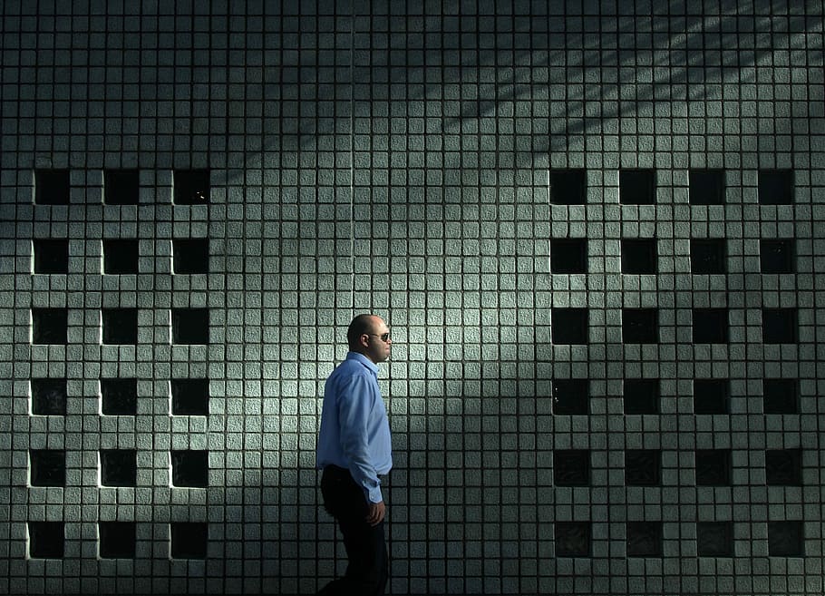 man in blue dress shirt walking near gray concrete wall, man walking beside white and gray wall HD wallpaper