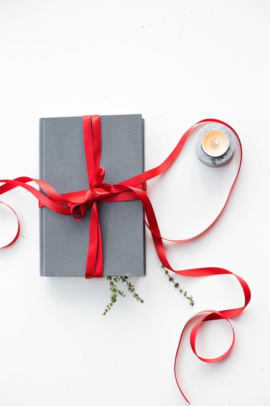 gray book wrapped with red ribbon beside teallight candle, gray book with red ribbon beside votive candle HD wallpaper