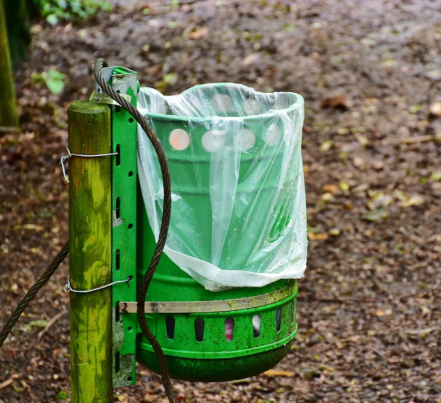 selective focus photo of green metal can with plastic bag, garbage can