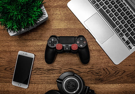 Silver Macbook Beside Black Sony Ps4 Dualshock 4, Silver Iphone 6, and Round Black Keychain on Brown Wooden Table HD wallpaper