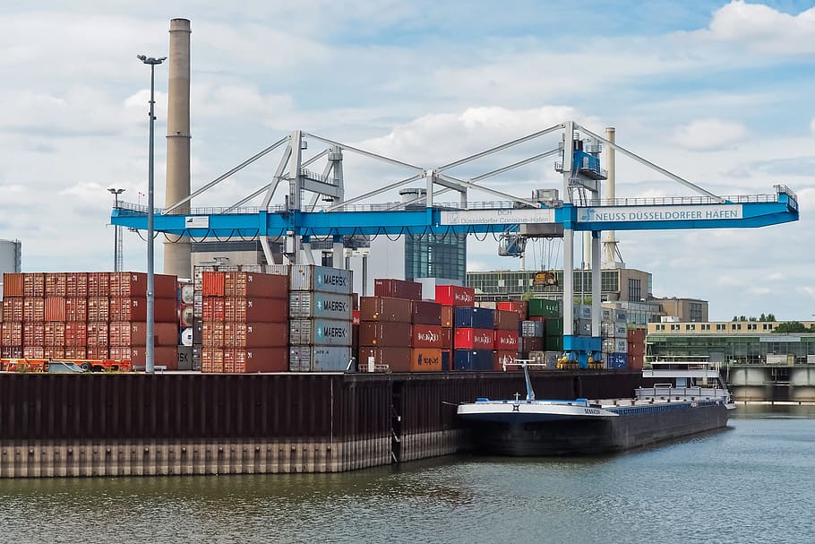 blue and white intermodal container crane near shipping boat and port