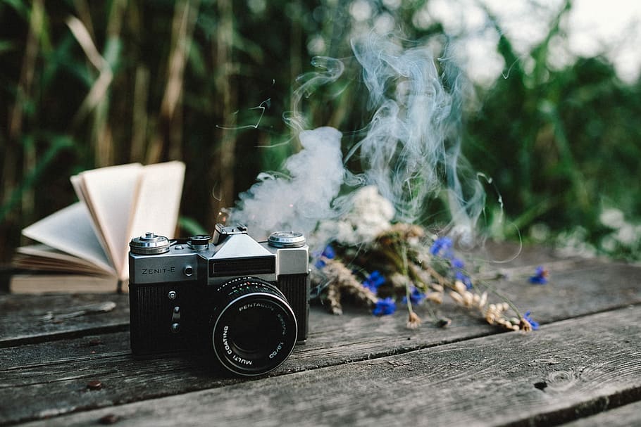 Colorful smoke bomb, book and vintage camera, wooden desk, wooden pier