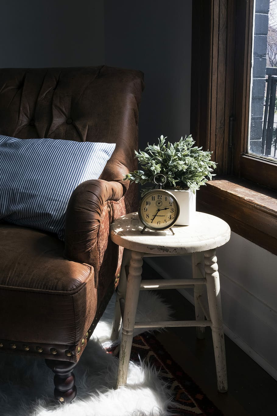 brown leather padded sofa armchair next to white wooden stool chair with round gray metal analog clock, gray metal alarm clock on wooden stool at 2:35 HD wallpaper