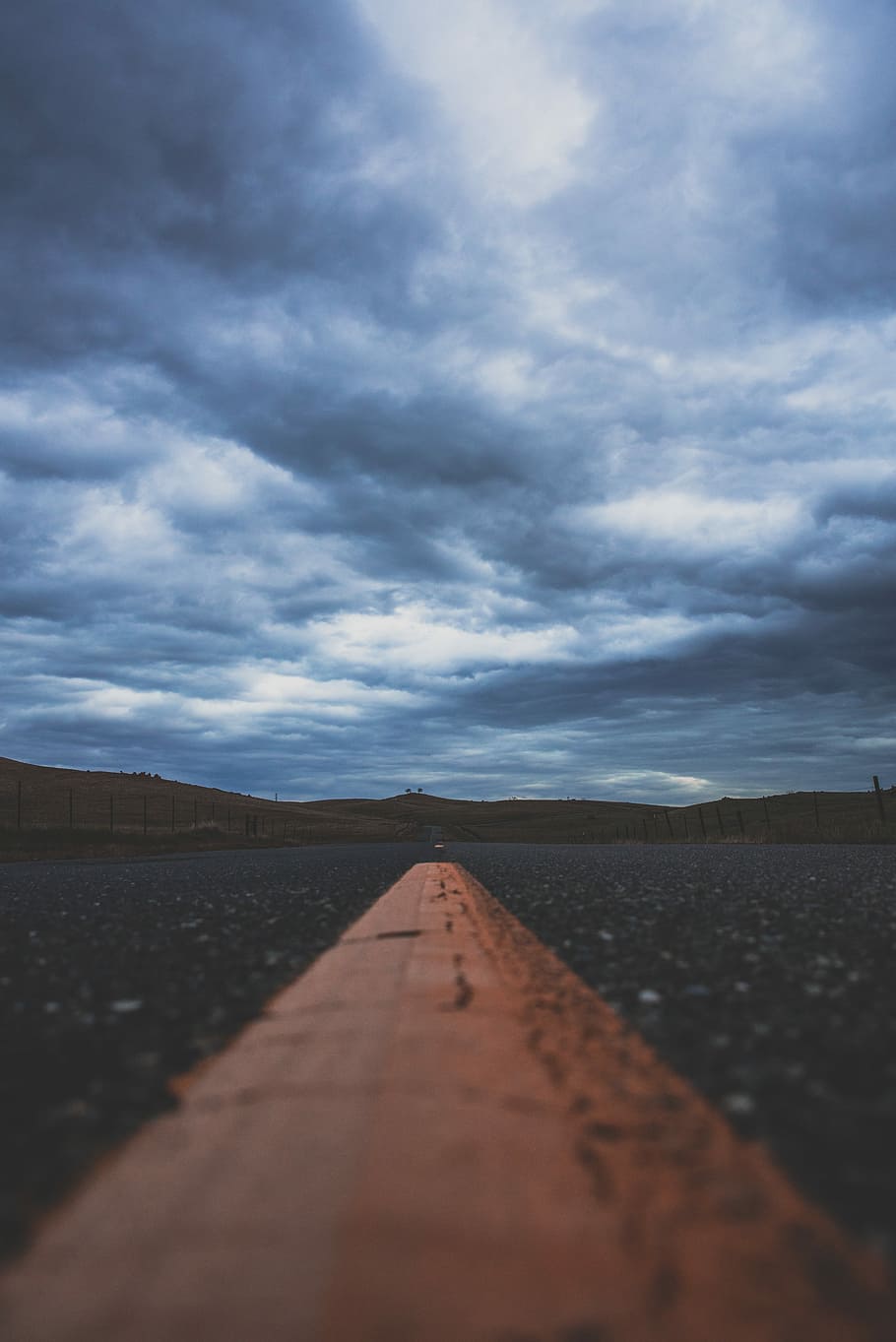 low angle photography of gray concrete road under cumulus clouds, yellow road line under gray sky HD wallpaper