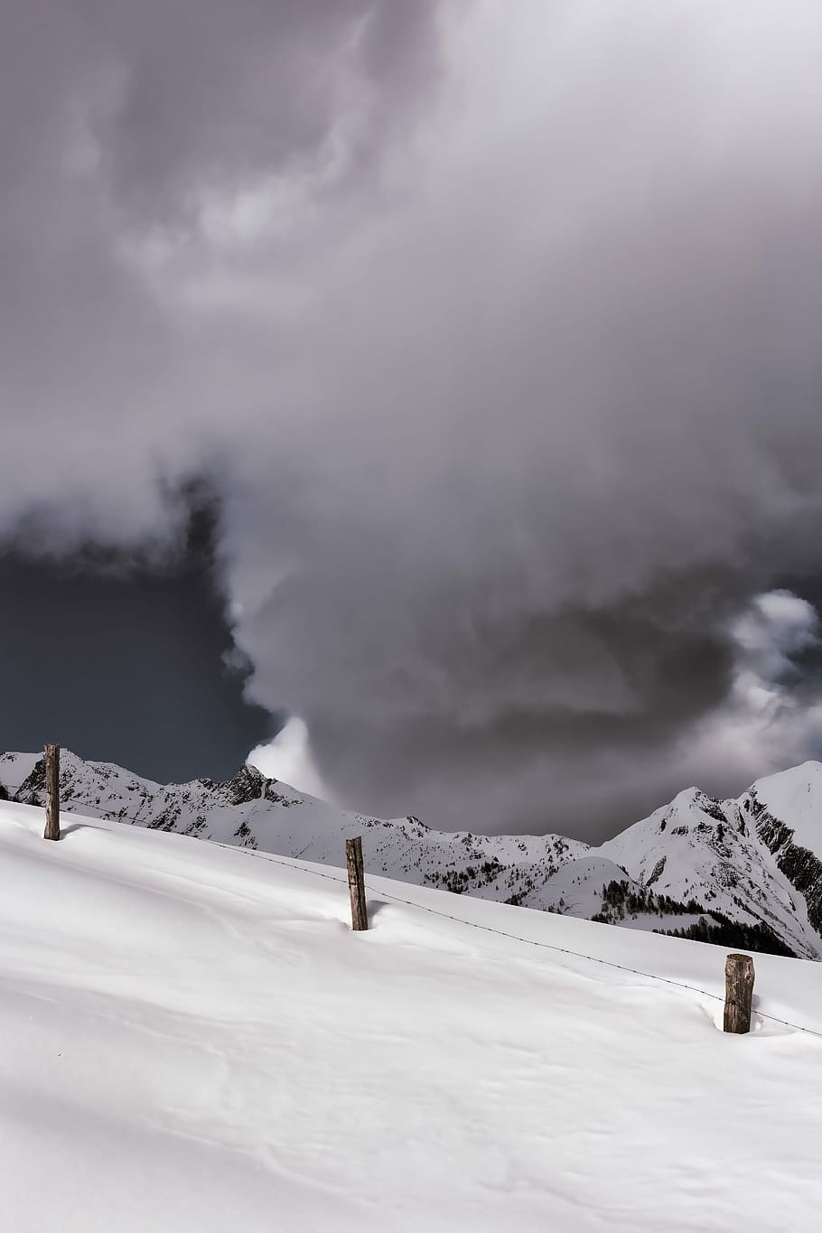 brown wooden post and barbed wire fence on snow surface overlooking mountains under grey cloudy sky, snow on top of the mountain under cloudy sky HD wallpaper