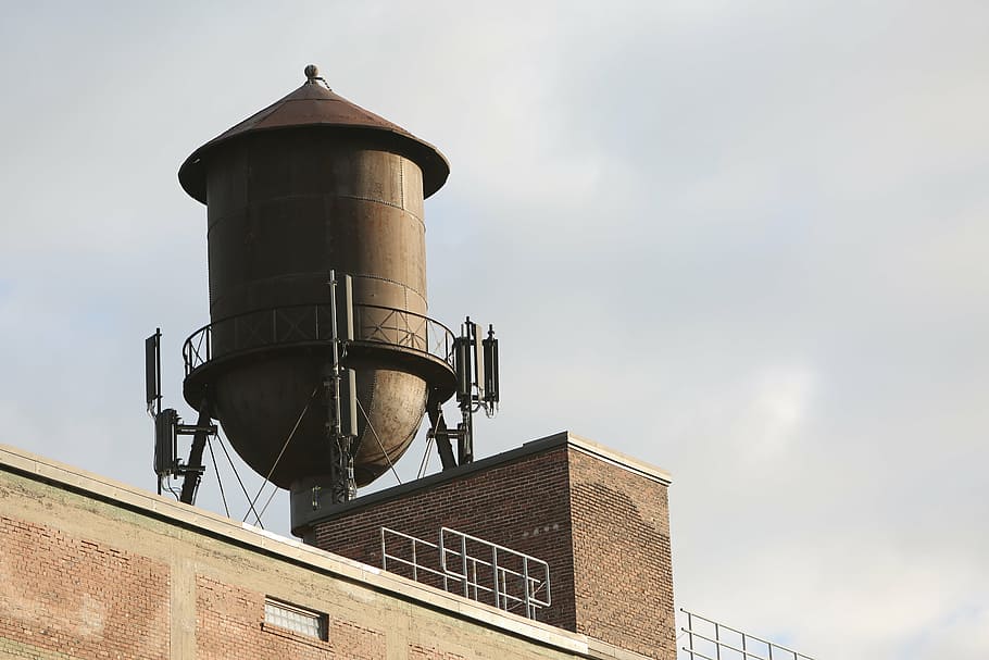 low-angle photography of gray rain water tank on top of building under nimbus clouds HD wallpaper