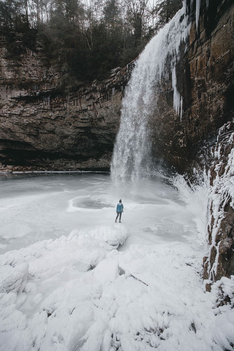 person standing on frozen waterfall outdoor during daytime, aerial view of person standing near waterfalls HD wallpaper