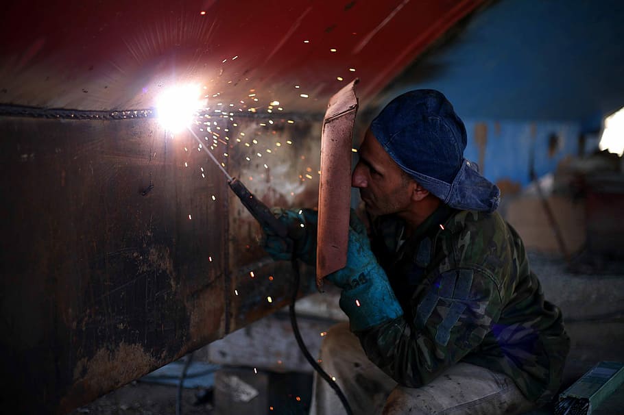man welding the brown metal board, man soldering black metal sheet HD wallpaper
