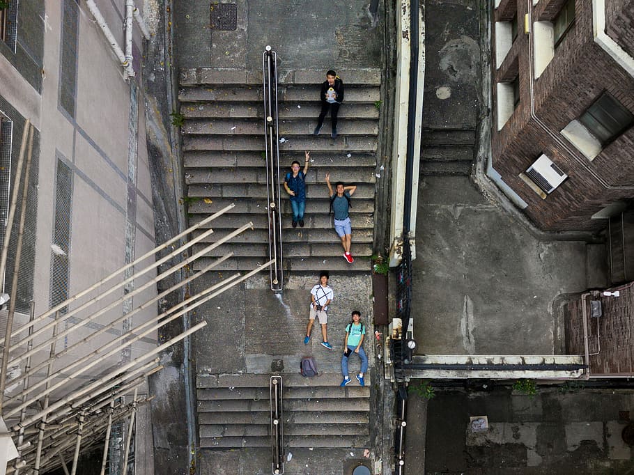 aerial photography of five person's lying on sair, aerial photography of five people lying on gray concrete stairway during daytime HD wallpaper